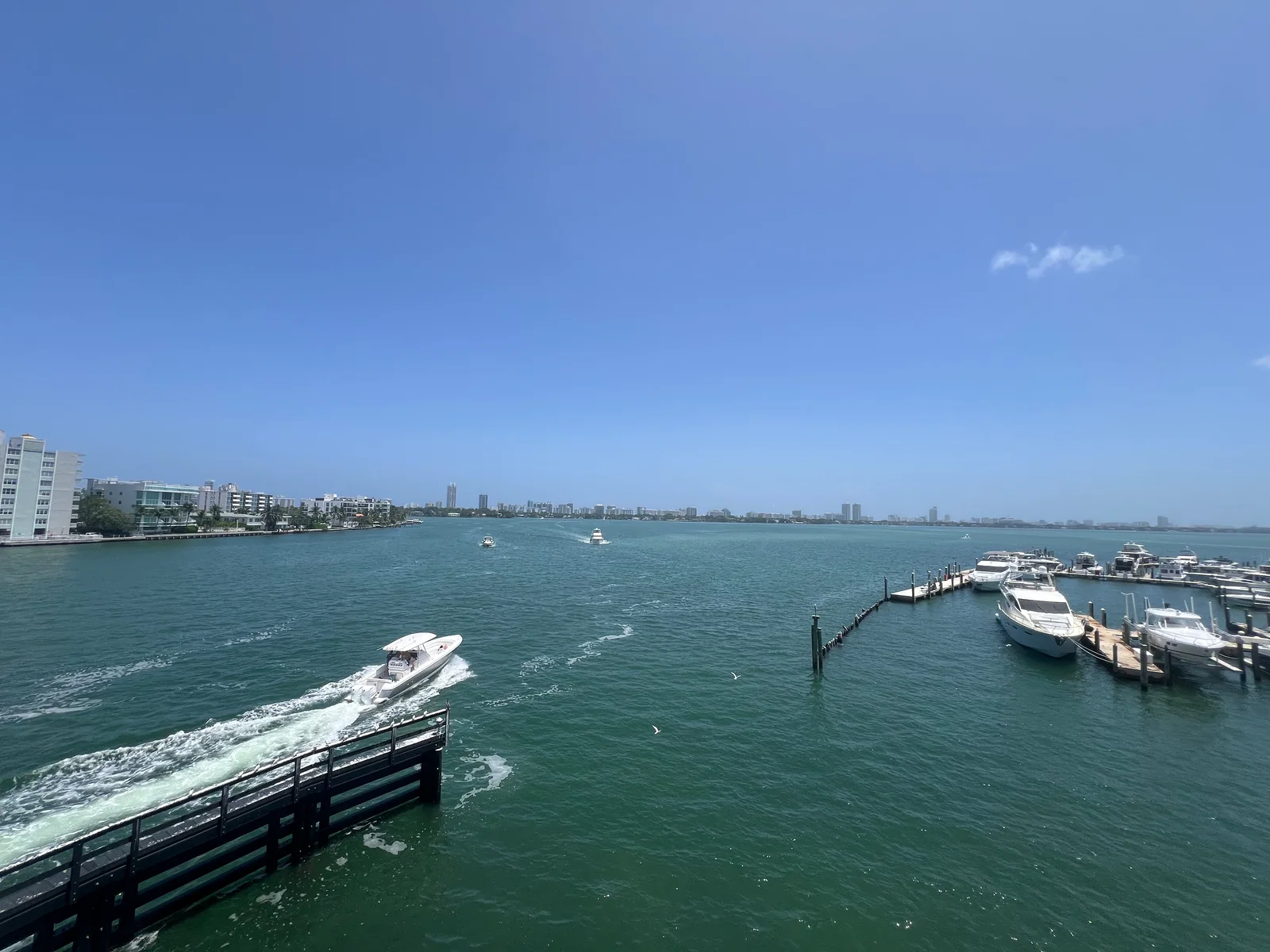 A boat moving through the bay beside marina docks