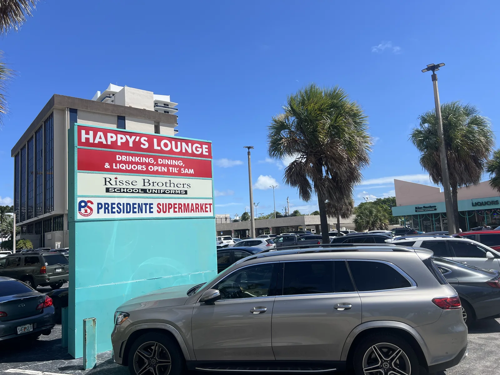 The roadside plaza sign brings Happy’s Lounge and Presidente Supermarket together in one neighborhood landmark.