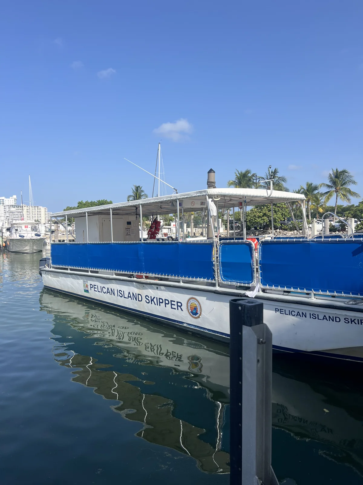 The blue-and-white Pelican Island Skipper moored at a dock, with its name visible on the hull