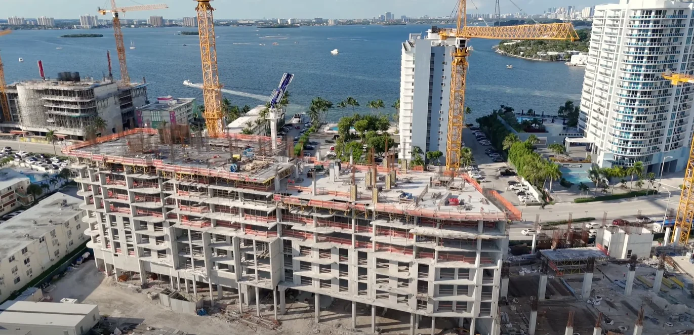 Elevated view of the rear of Shoma Bay and the new Publix under construction, with cranes and Biscayne Bay behind.