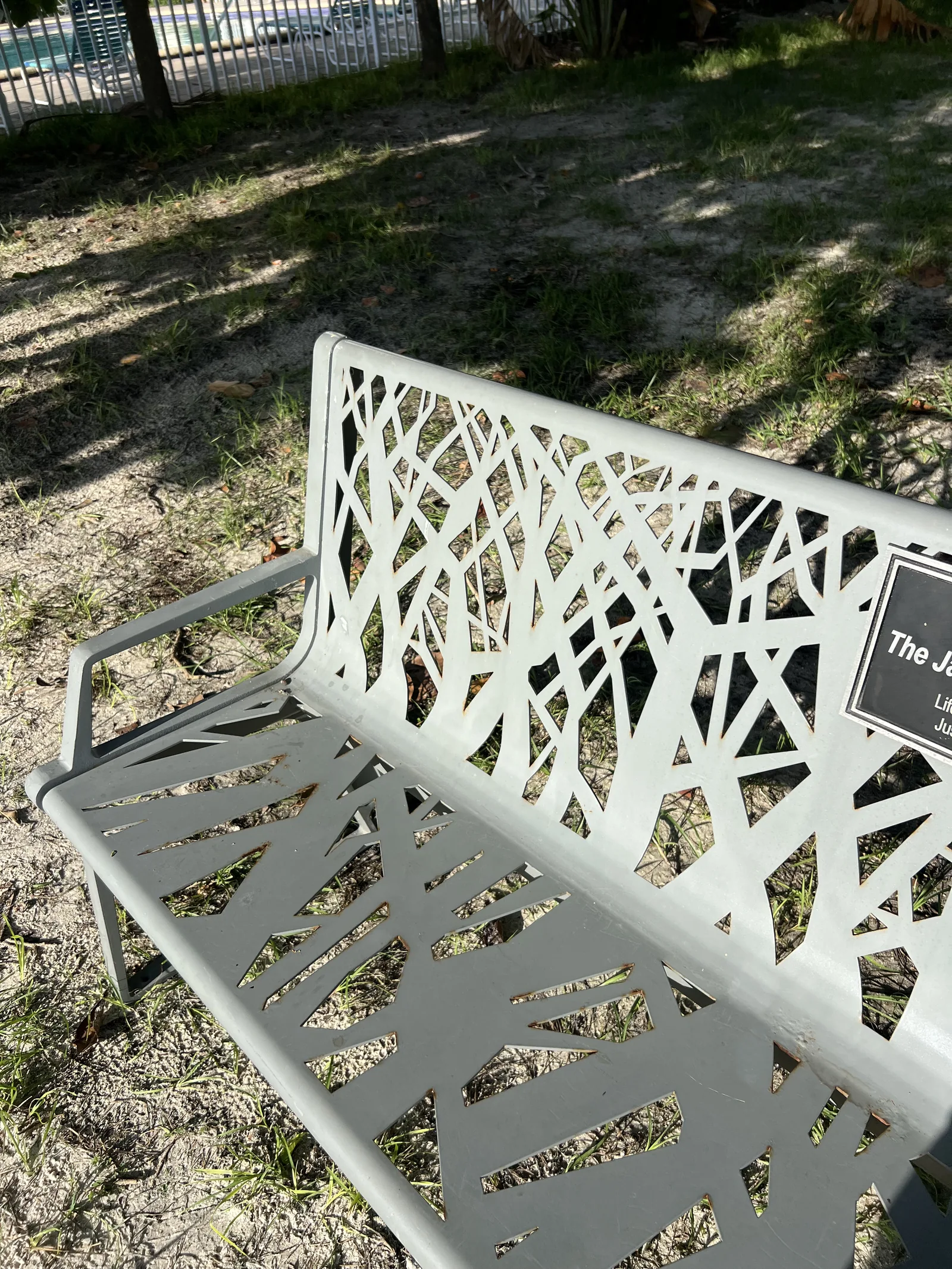 Close-up of the Jacob family’s branch-pattern metal bench; the dedication plaque is partly outside the frame