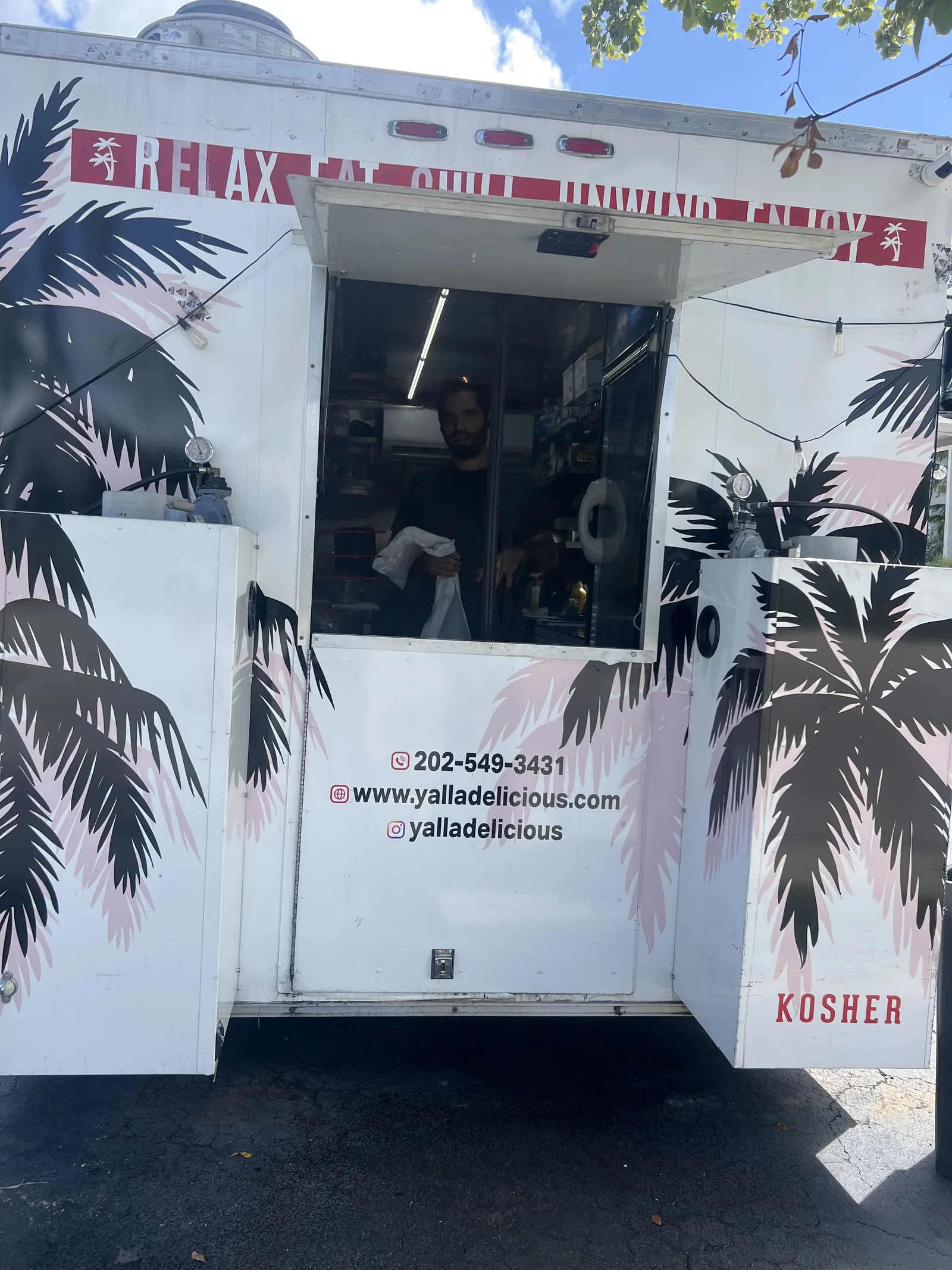 The rear of the Yalla Delicious truck, with its pink lettering and open door.